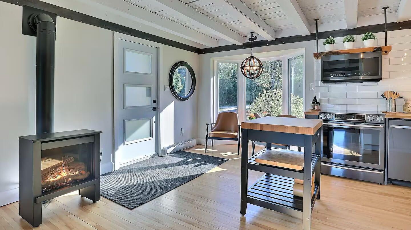 Cuisine lumineuse du chalet Le Monarque près de Magog avec îlot central, grandes fenêtres et foyer moderne